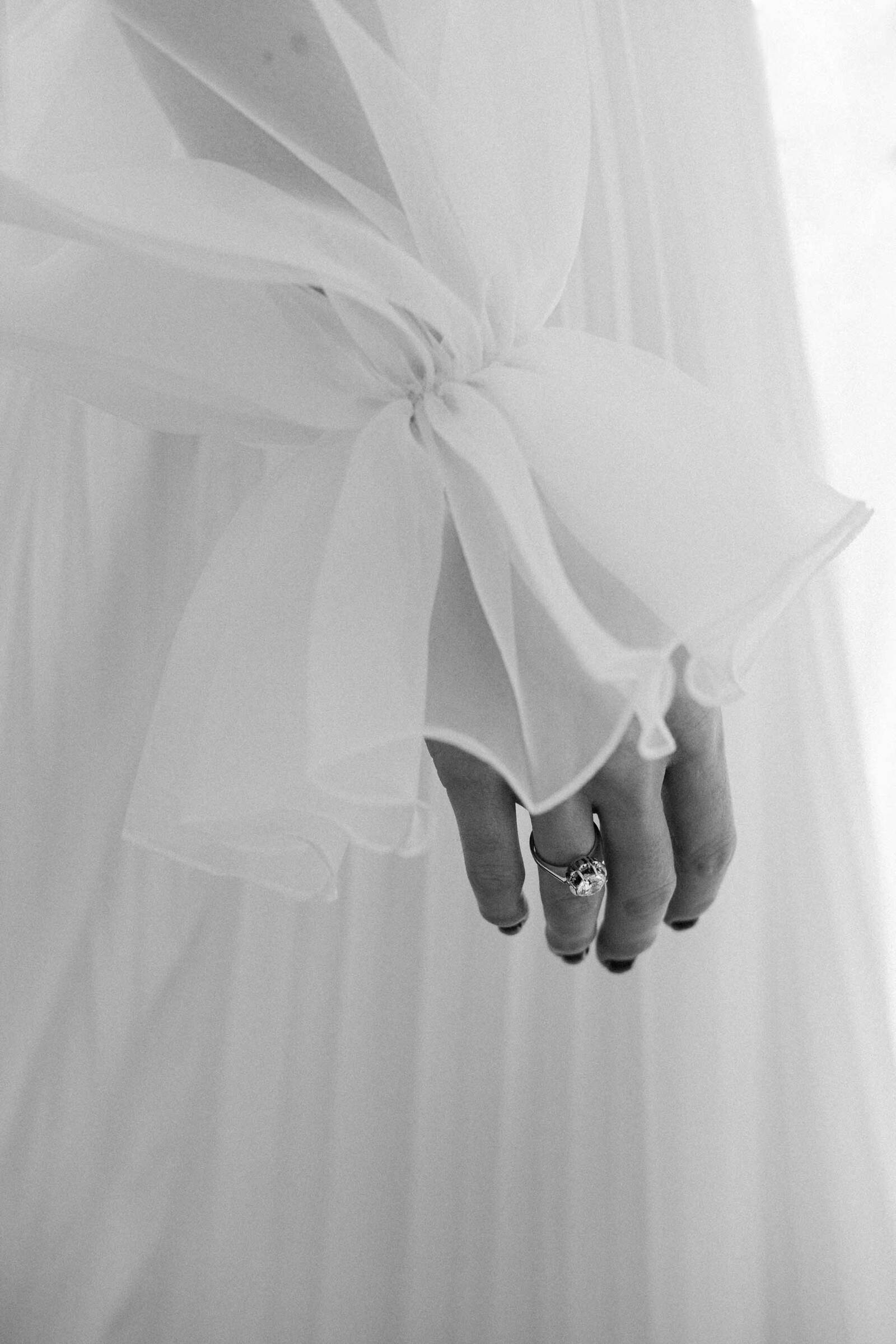 detalle de la manga de un vestido de novia con anillo de compromiso